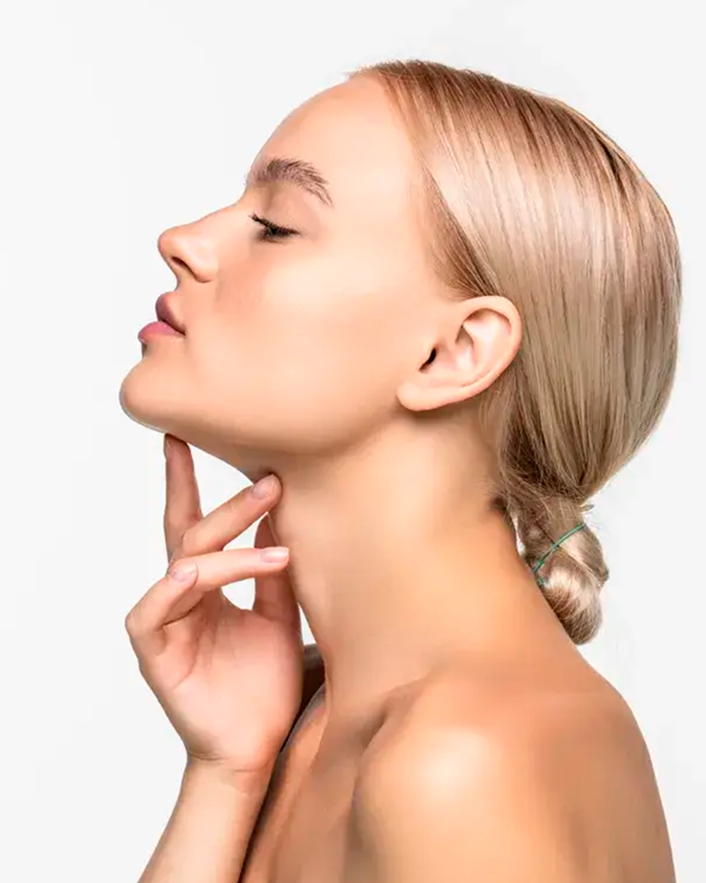 Mulher de perfil com a pele iluminada, tocando o contorno do rosto
